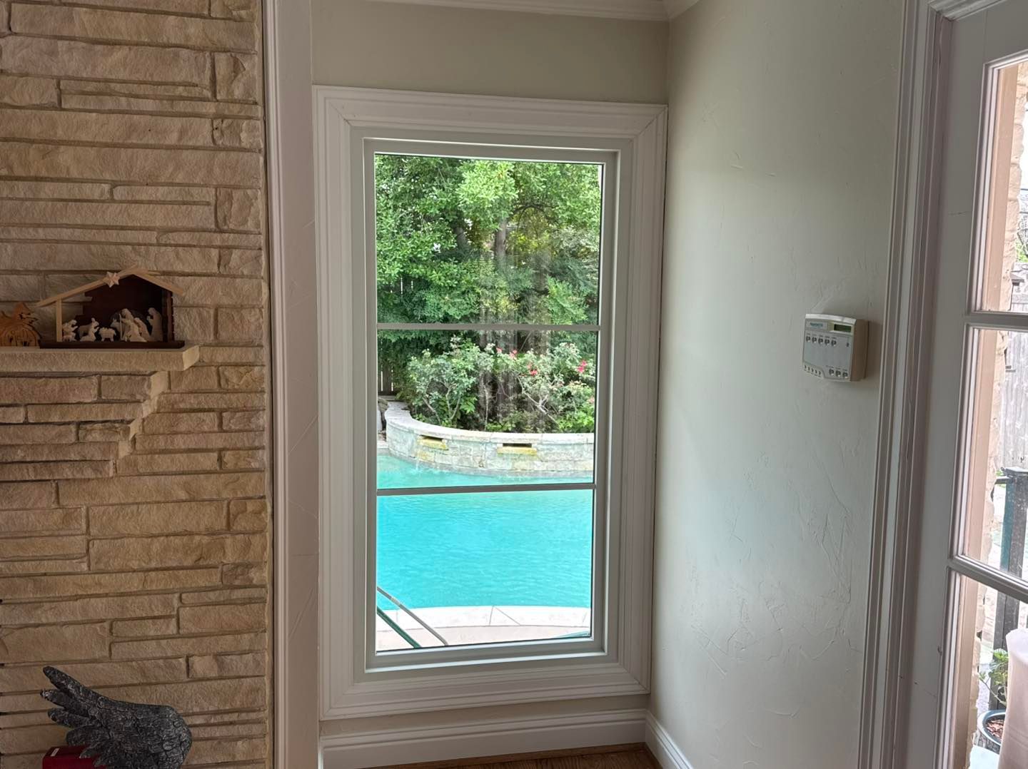 A living room with a window looking out to a pool.