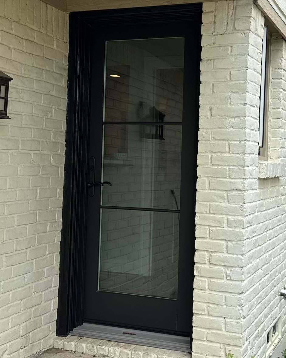 A black door is on a white brick building.
