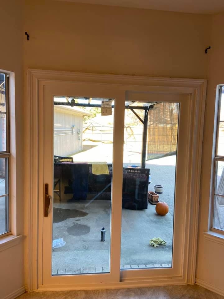 A room with a sliding glass door and two windows.