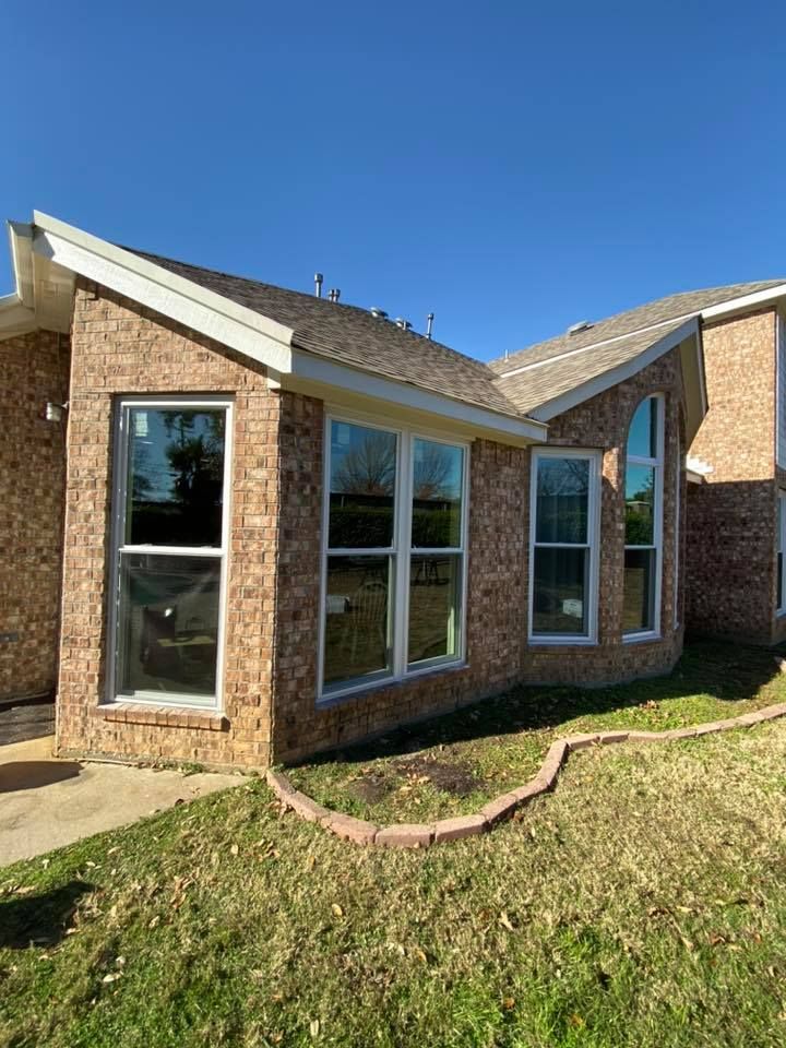 A brick house with a lot of windows and a blue sky in the background.