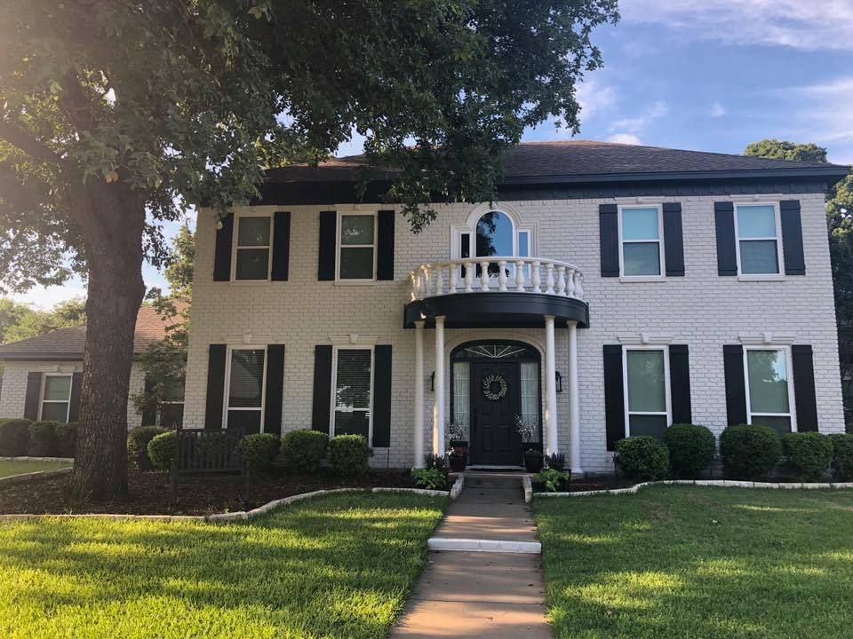 A white house with black shutters and a balcony