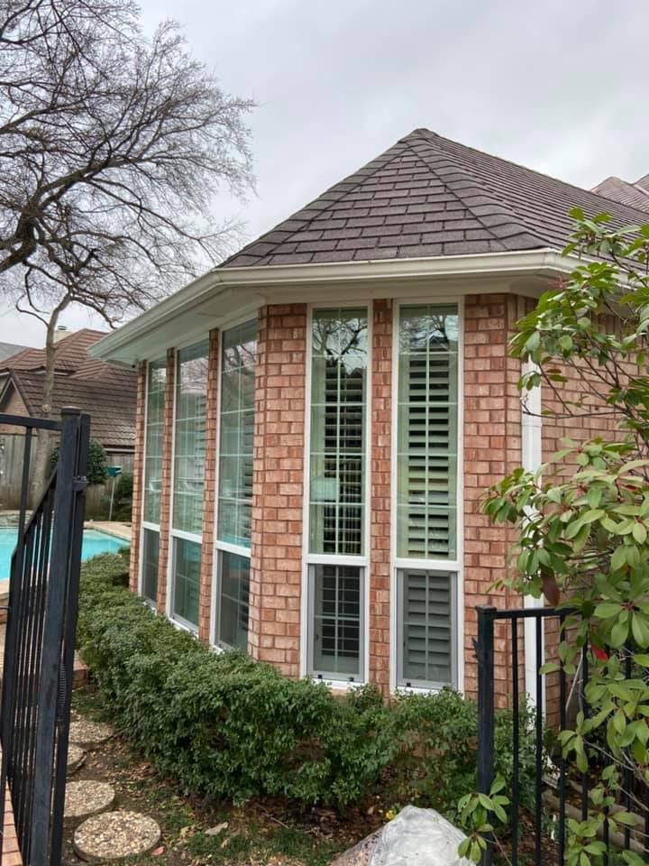 A brick house with a pool in the backyard and a lot of windows.