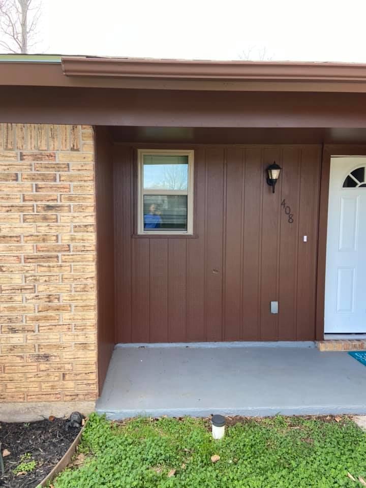 A brown house with a white door and a window.
