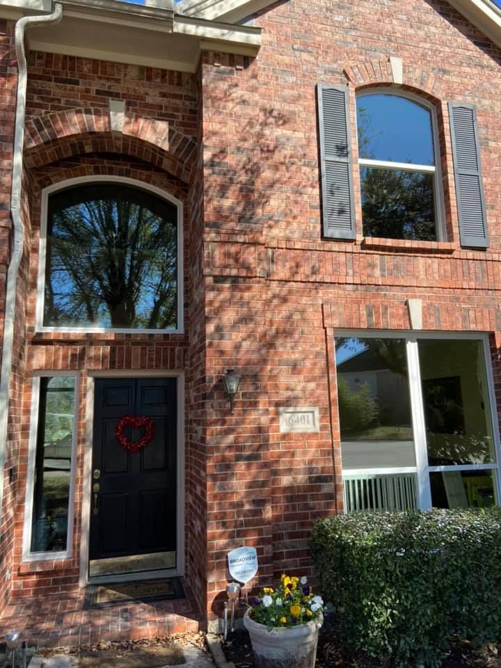 The front of a brick house with arched windows and shutters.