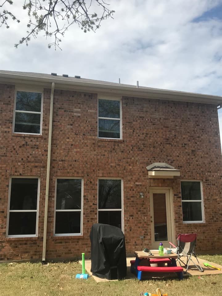 A brick house with a picnic table and grill in the backyard.