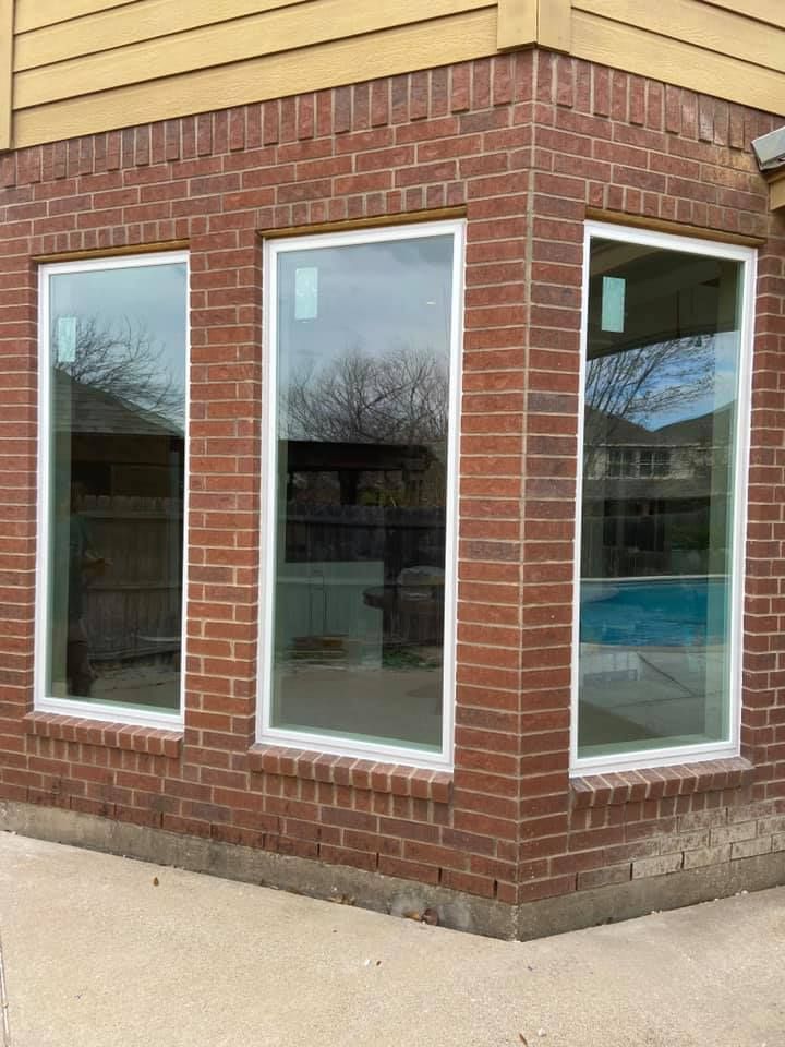A brick building with three windows and a pool in the background