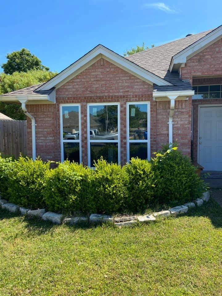 A brick house with a lot of windows and bushes in front of it