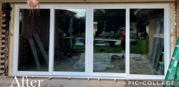 Newly installed white sliding glass doors in a brick framed opening, reflecting a backyard scene.
