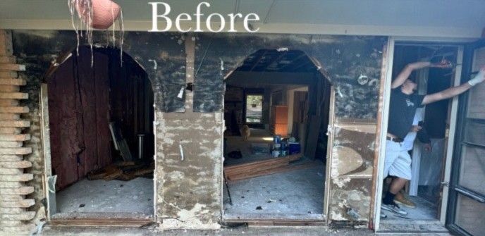 Interior doorway undergoing renovation; worker in doorway, arches, exposed framing.