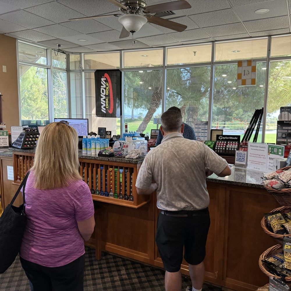 Golfers waiting in line at a pro shop checkout counter, highlighting the need for efficient golf course systems.