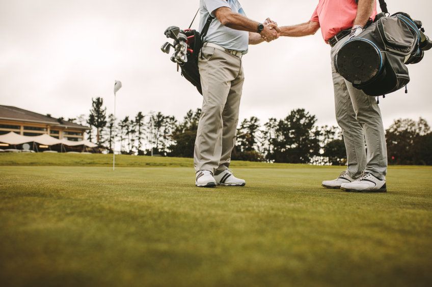 Golfers closing a round with a handshake, representing positive member experience and loyalty at successful clubs.