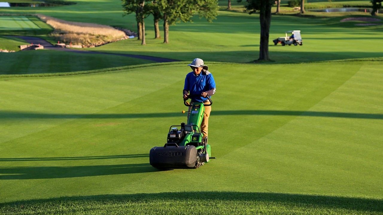 Greenskeeper using a push mower on the fairway, reflecting precision turf care in connected greenskeeping operations.