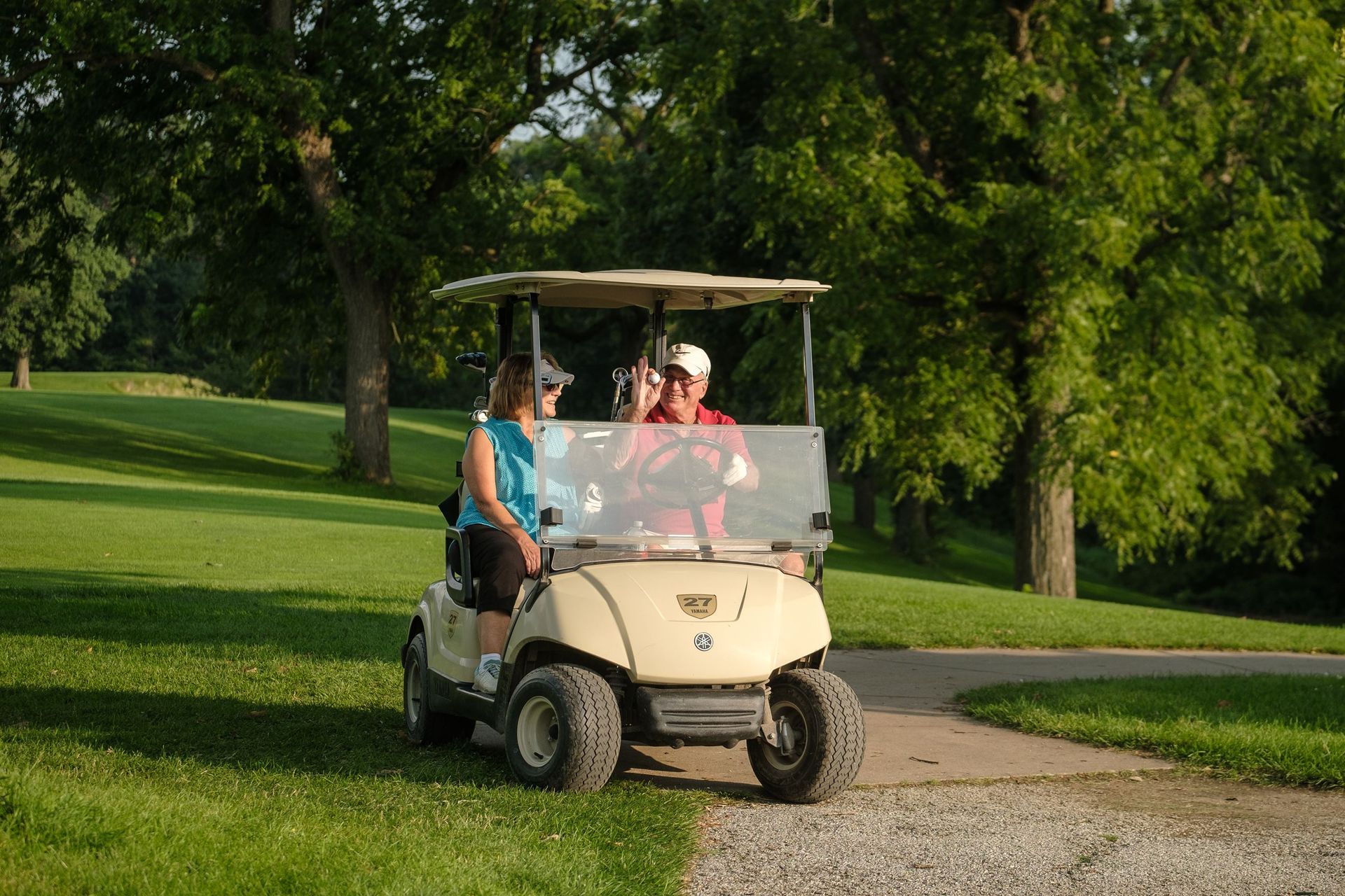 Beautiful golf course surrounded by trees and rolling hills under clear skies.