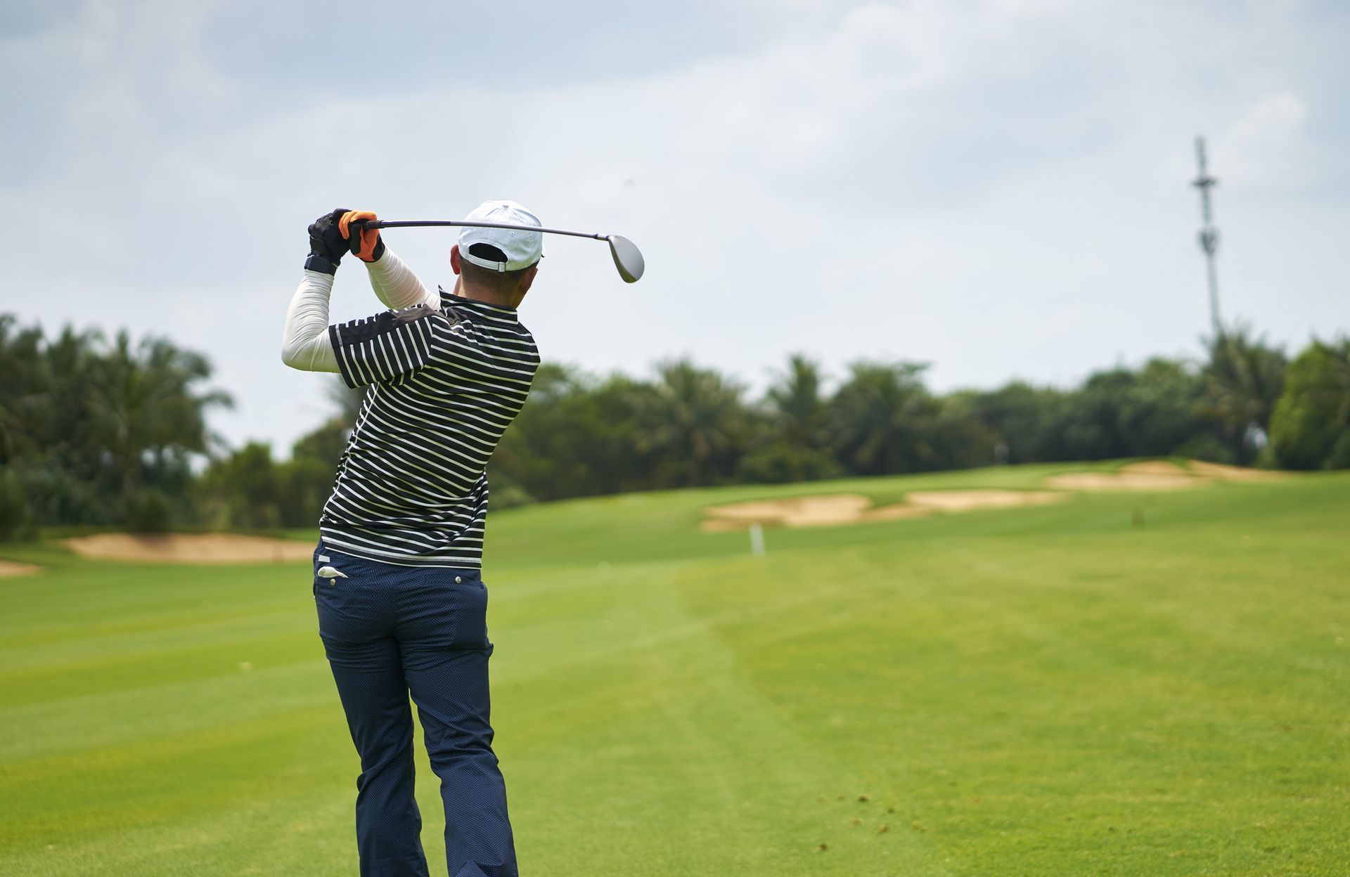 Amateur golfer making a confident swing with a hybrid club for better launch and forgiveness.