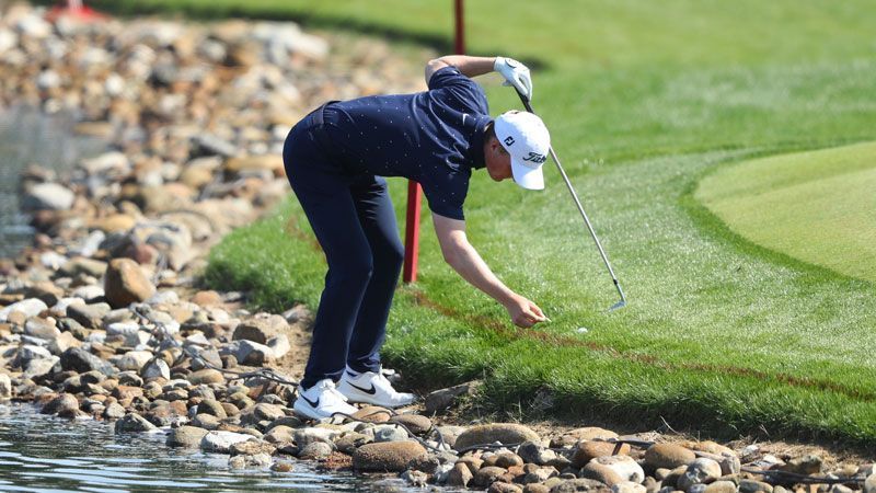 Golfer taking a penalty drop near a water hazard under official golf rules