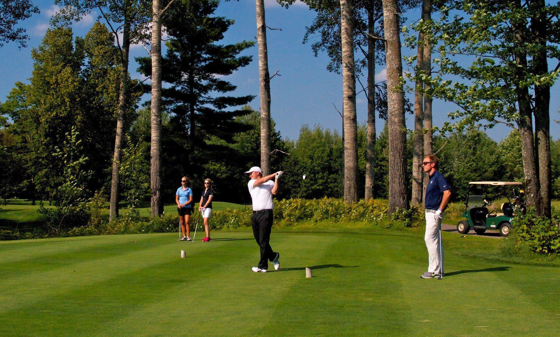 Group of amateur golfers teeing off on the first hole during a friendly match with handicaps in play