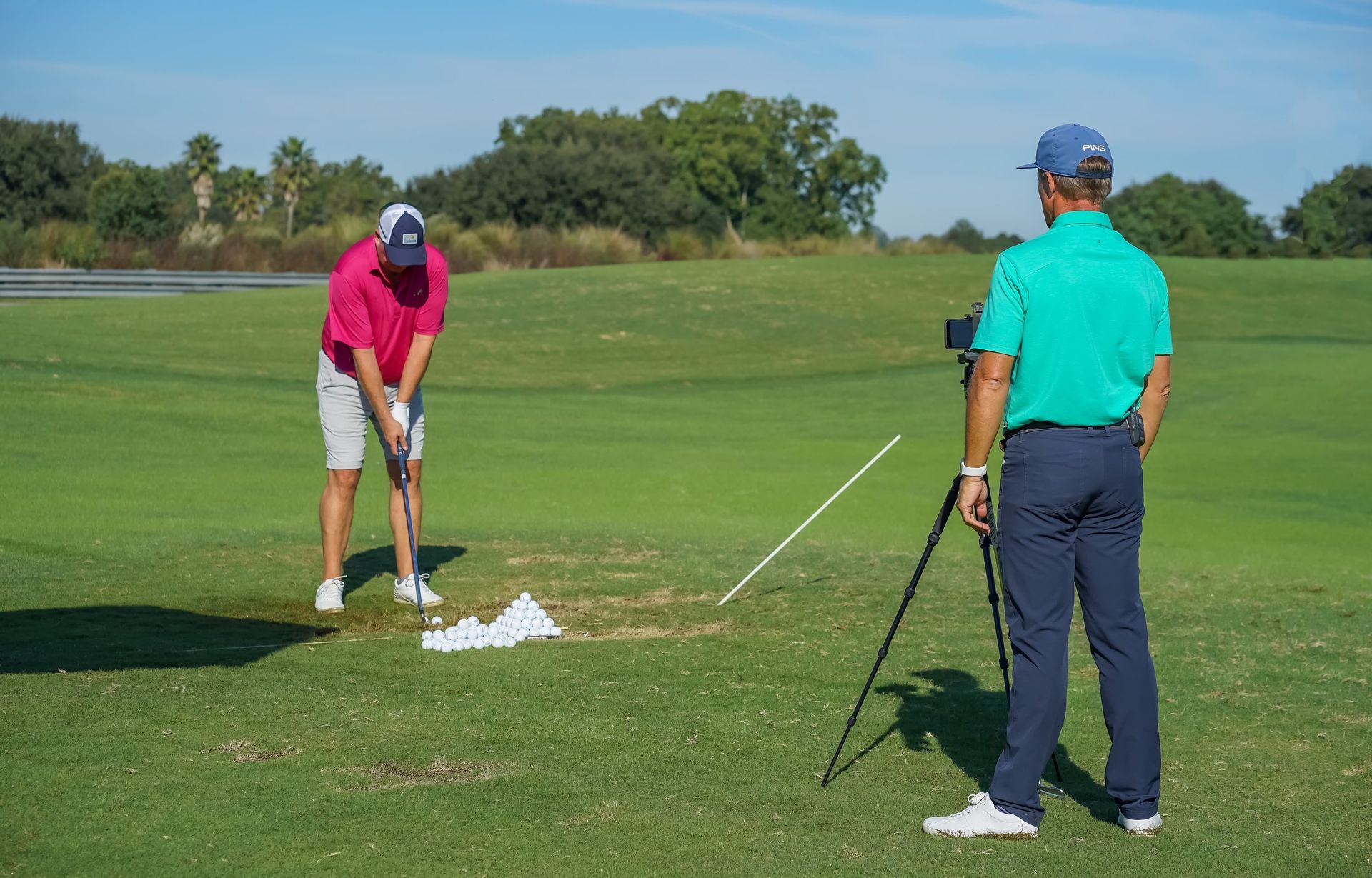 Golf instructor using modern swing analysis technology to film and improve a student’s golf swing on
