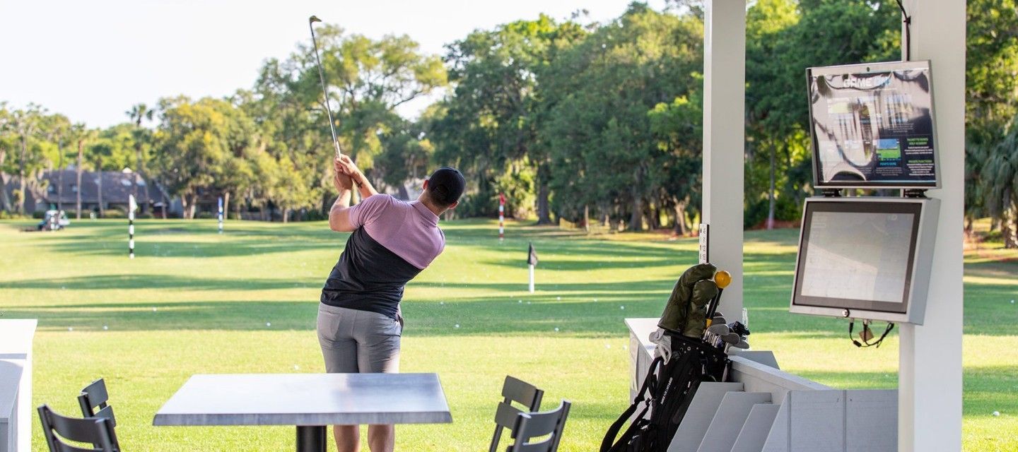 Modern golf course with state-of-the-art driving range and golfer practicing swing – future-forward.