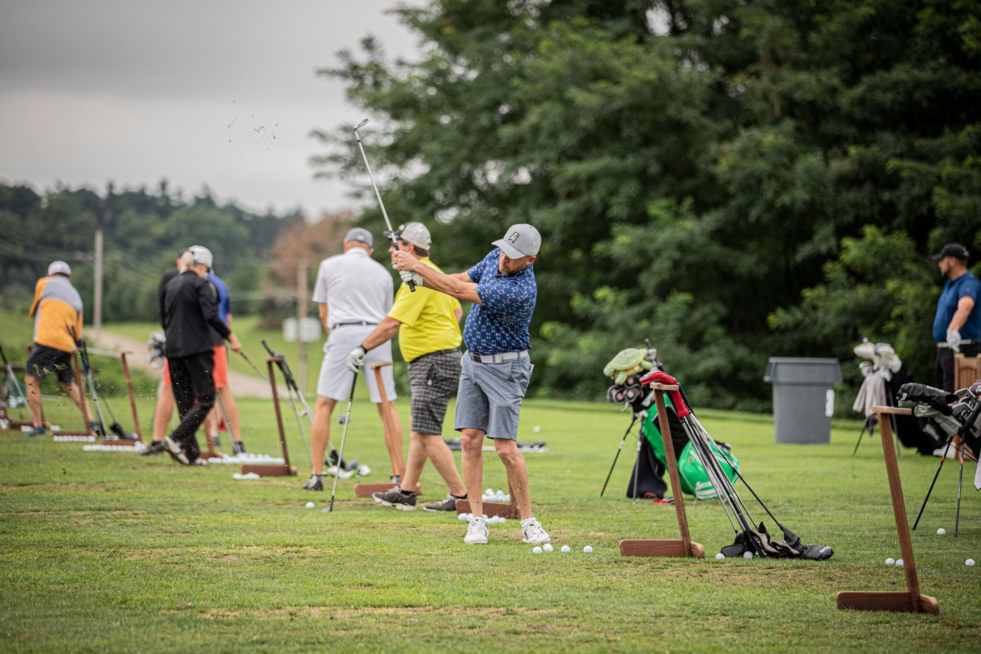 Golfers warming up on the driving range before their round begins.