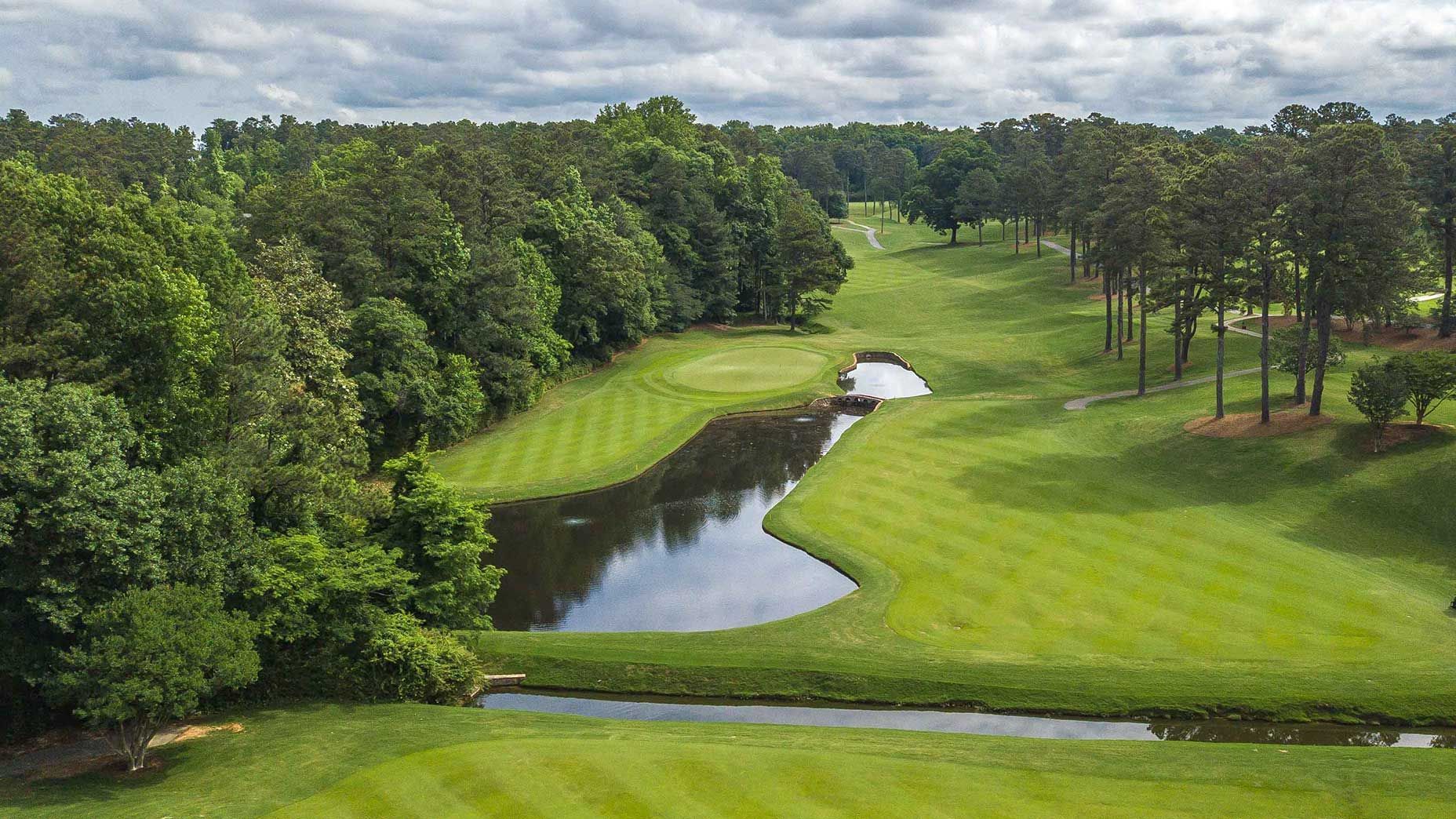 Beautiful golf course surrounded by trees and rolling hills under clear skies.