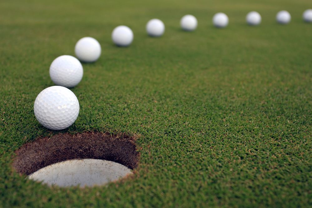Golf ball following break line into the hole on a green
