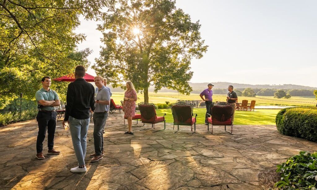 Golfers mingling at a social event hosted by Icon Golf, featuring outdoor seating, drinks, and a relaxed club atmosphere.