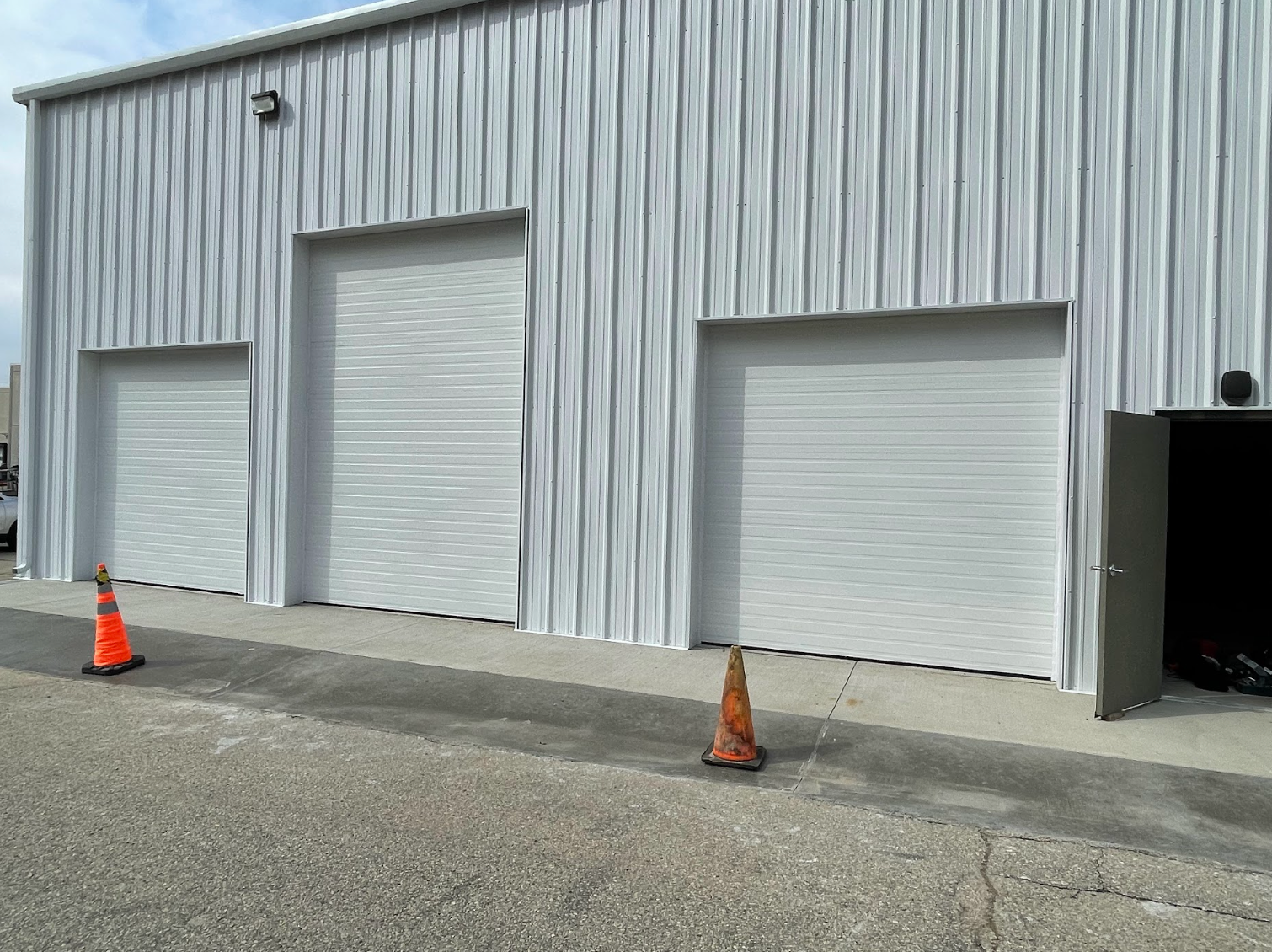 A white building with orange cones in front of it.