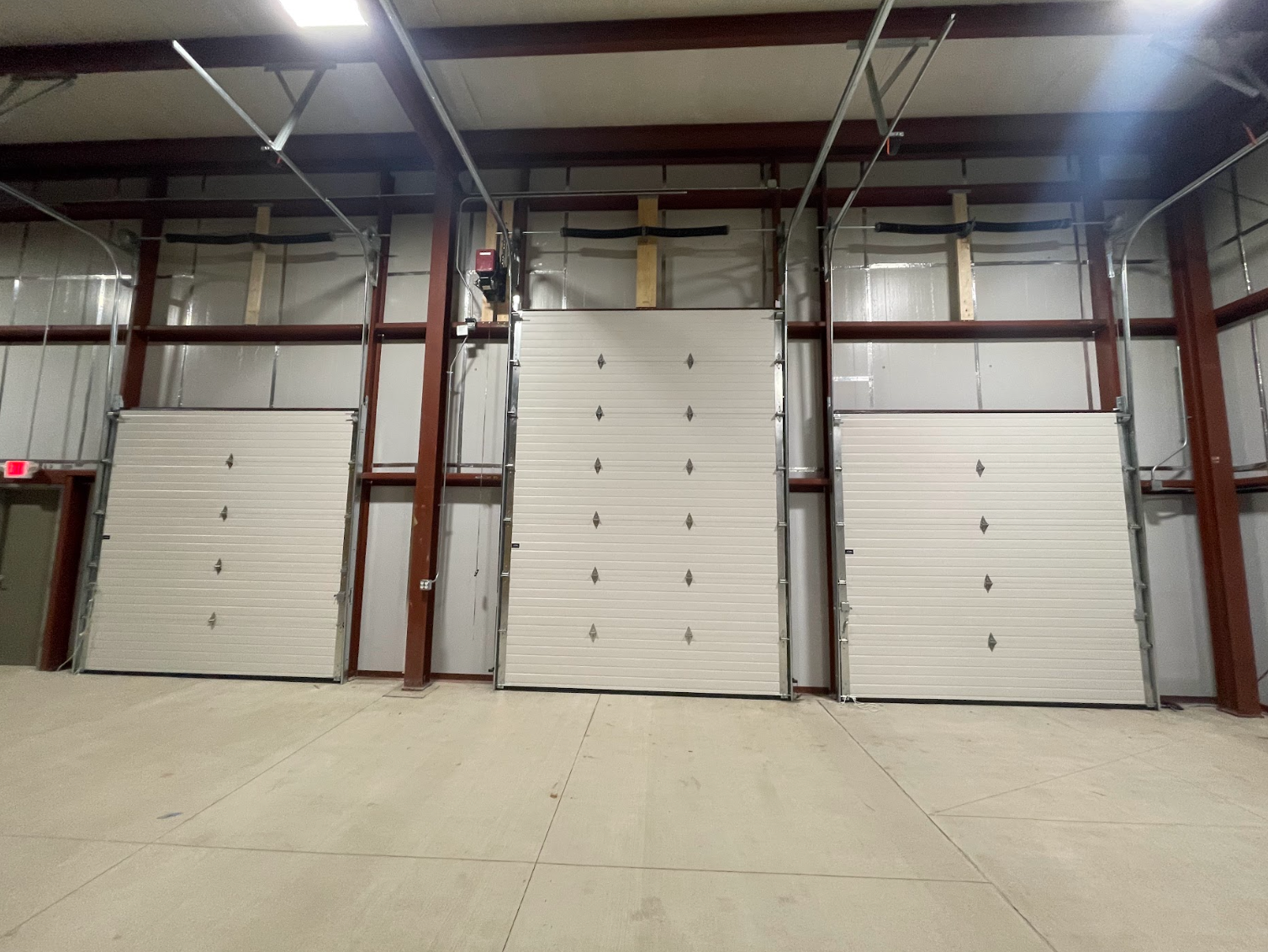 Three garage doors are open in an empty building