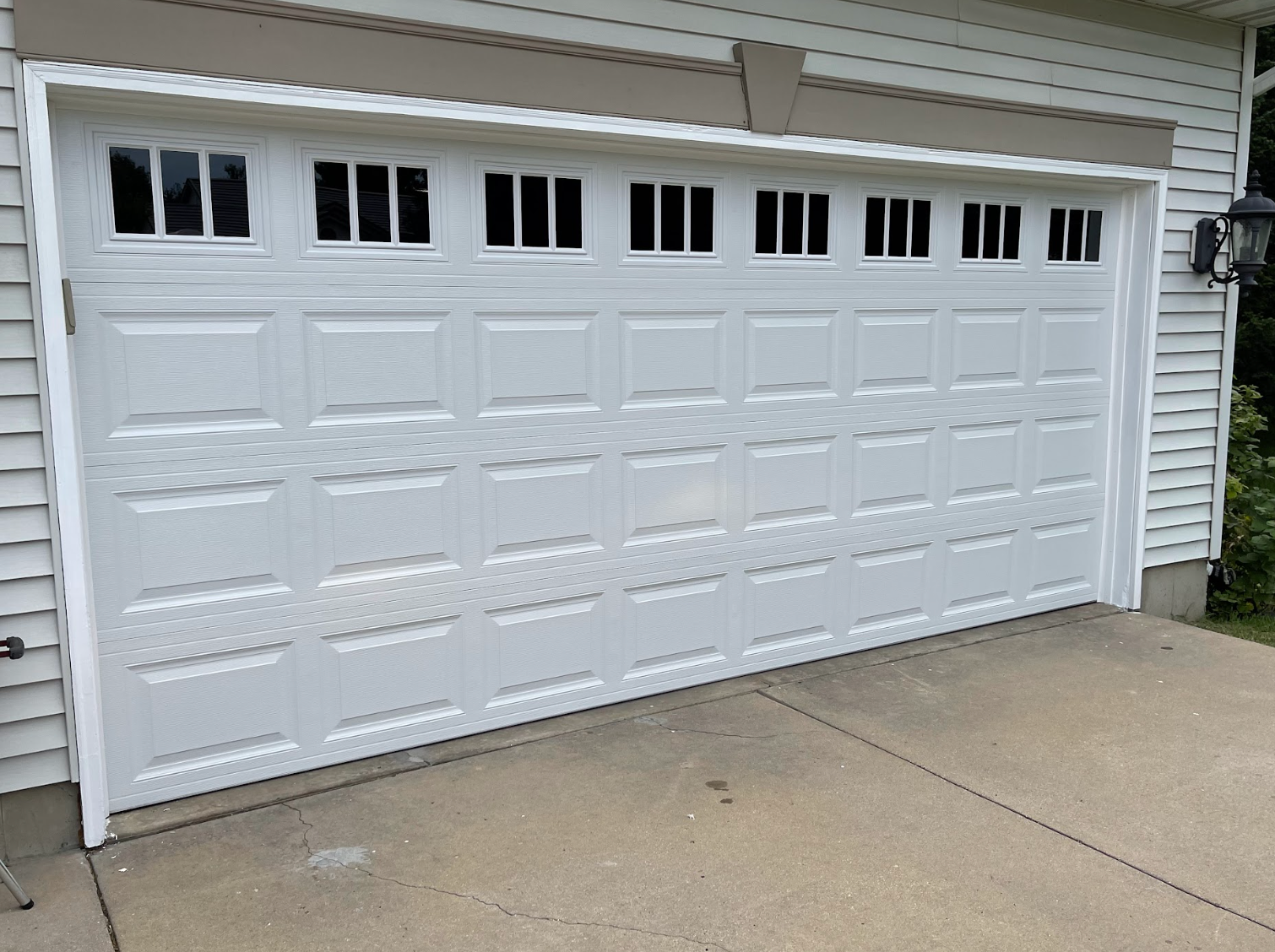 A white garage door is sitting in front of a house.