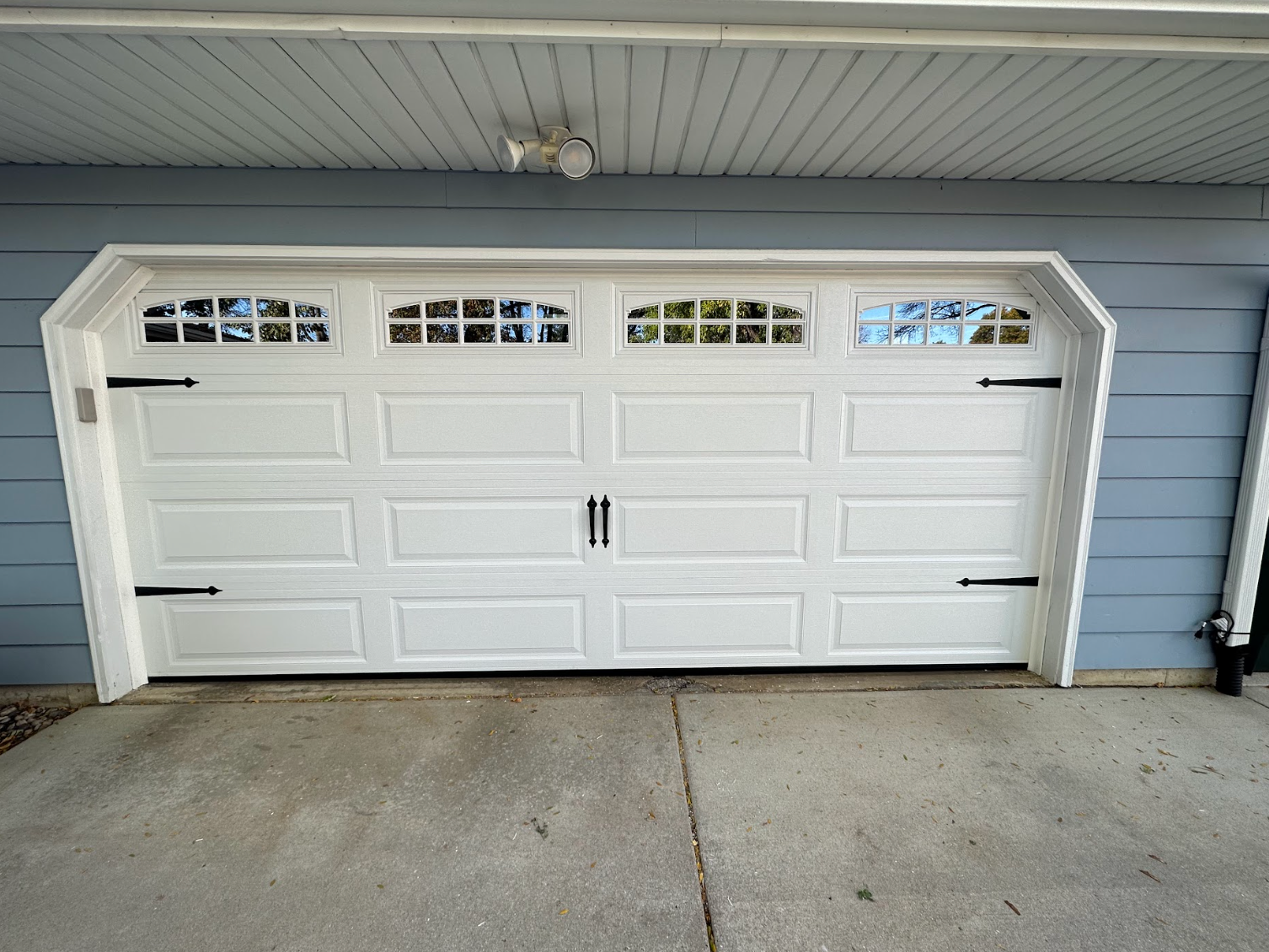 A white garage door with a blue house in the background