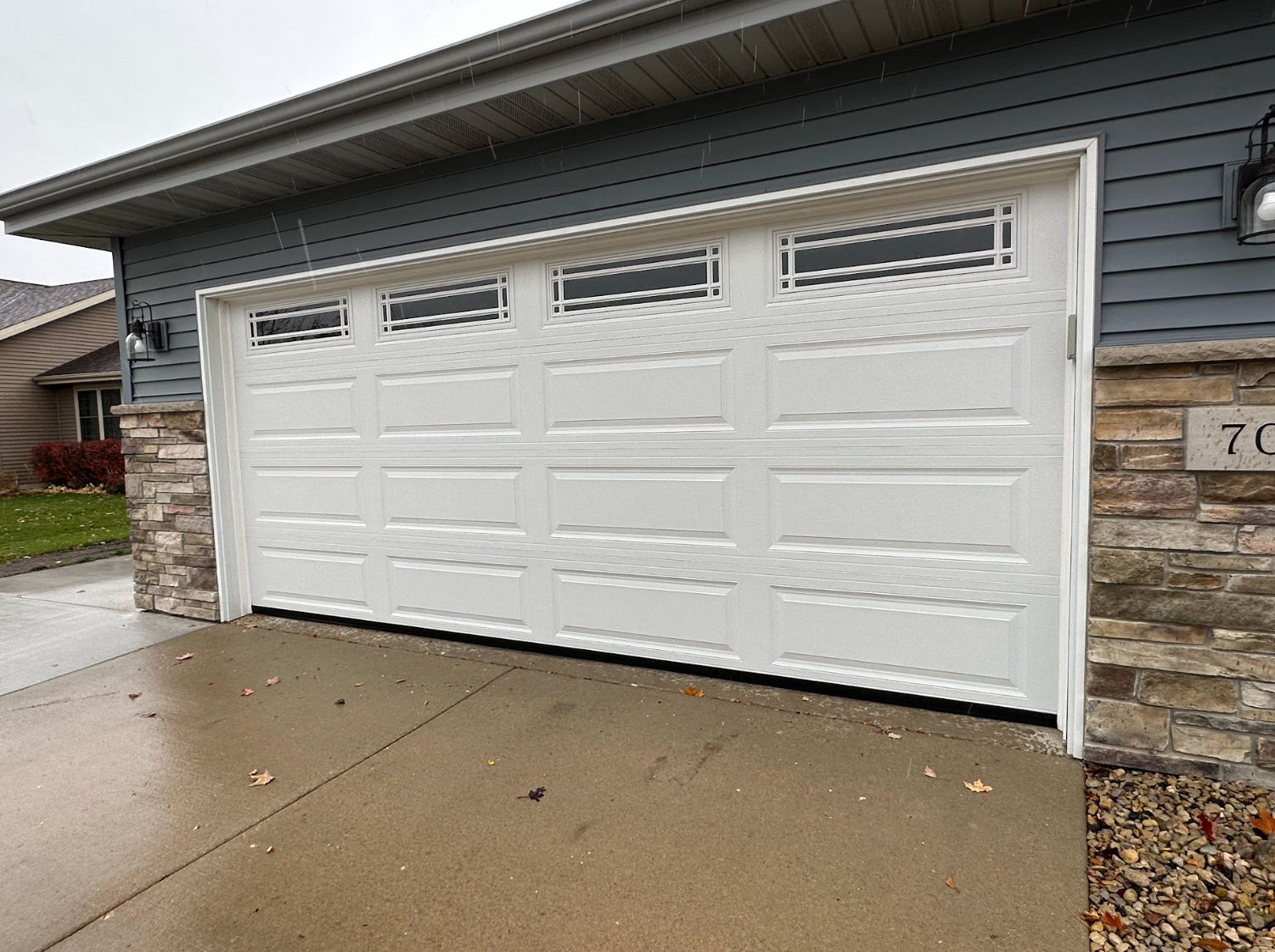 A white garage door is open in front of a house.