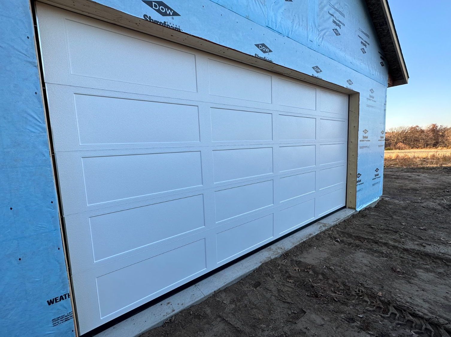 A white garage door is sitting on the side of a building.