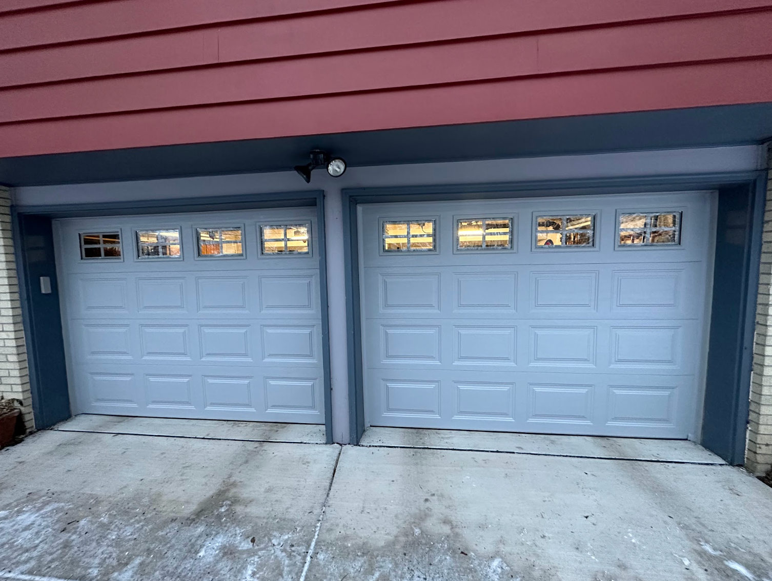 A couple of garage doors are sitting next to each other in front of a house.