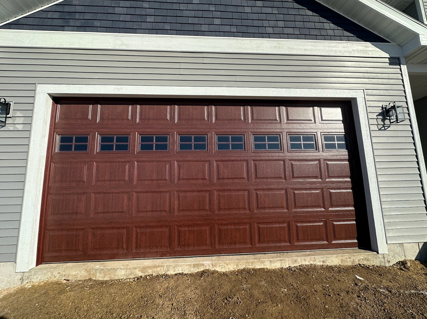 A brown garage door is sitting in front of a house.