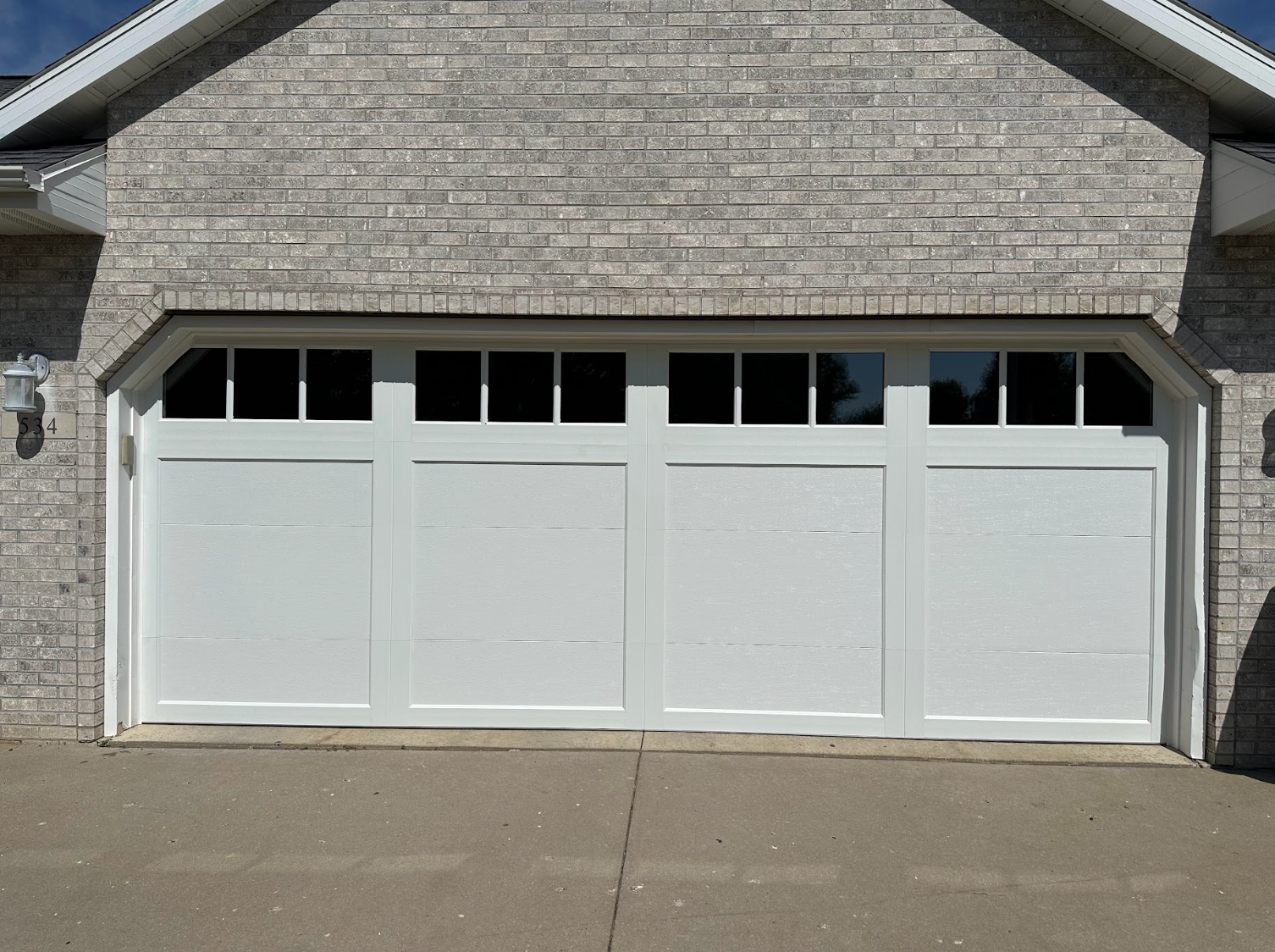 A white garage door is on a brick building