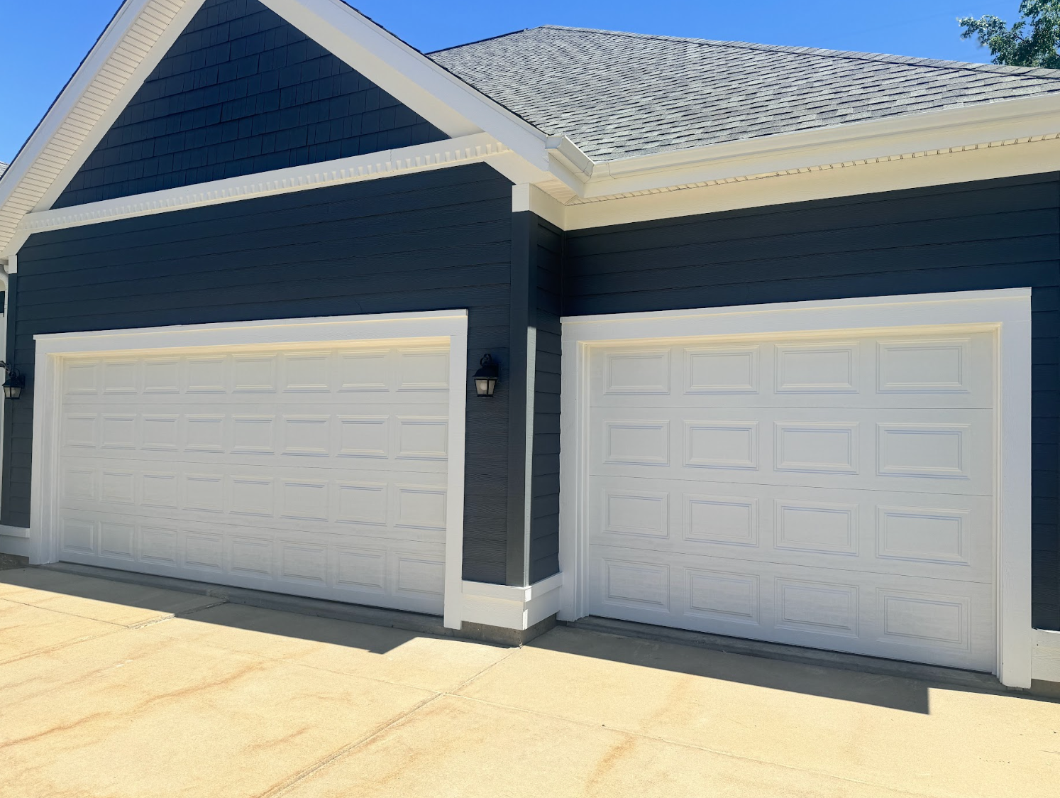 A black and white house with two white garage doors.