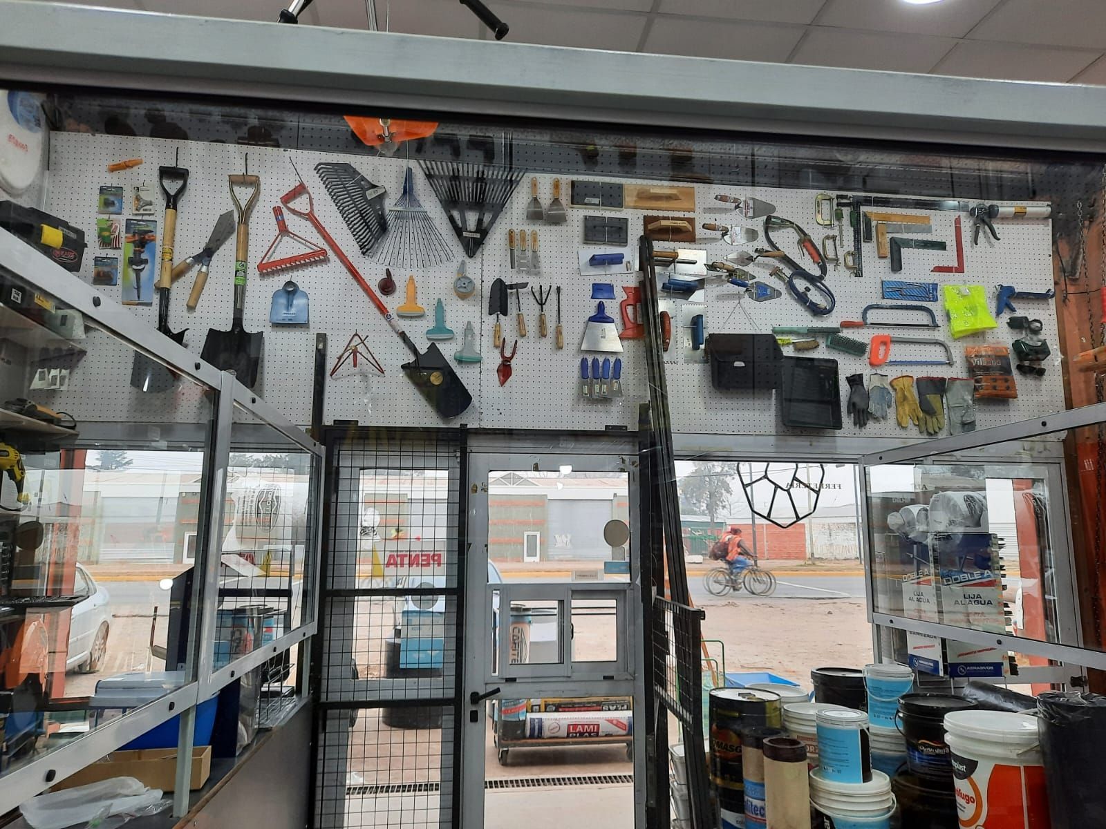 Interior de una pequeña tienda con herramientas y suministros expuestos en las paredes y estantes.