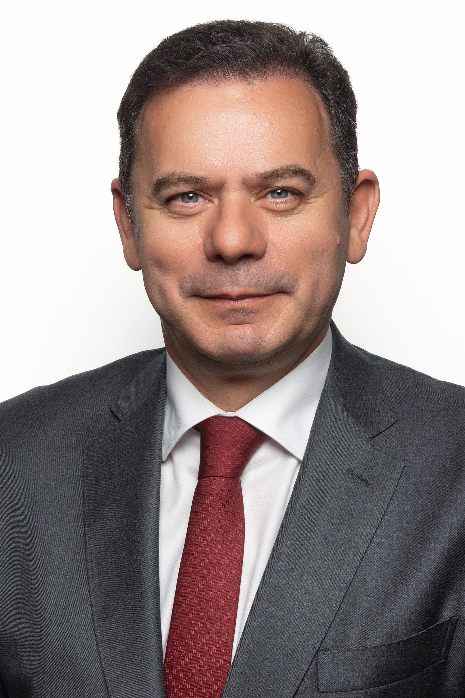 Retrato institucional de dirigente em contexto oficial, com iluminação sóbria