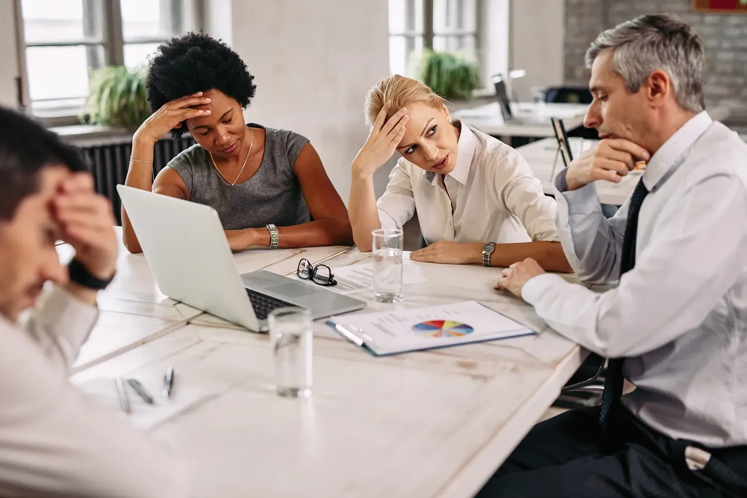 A group of people are sitting around a table with a laptop.