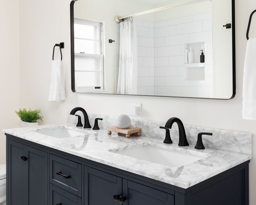 A bathroom with two sinks , a mirror and a toilet.