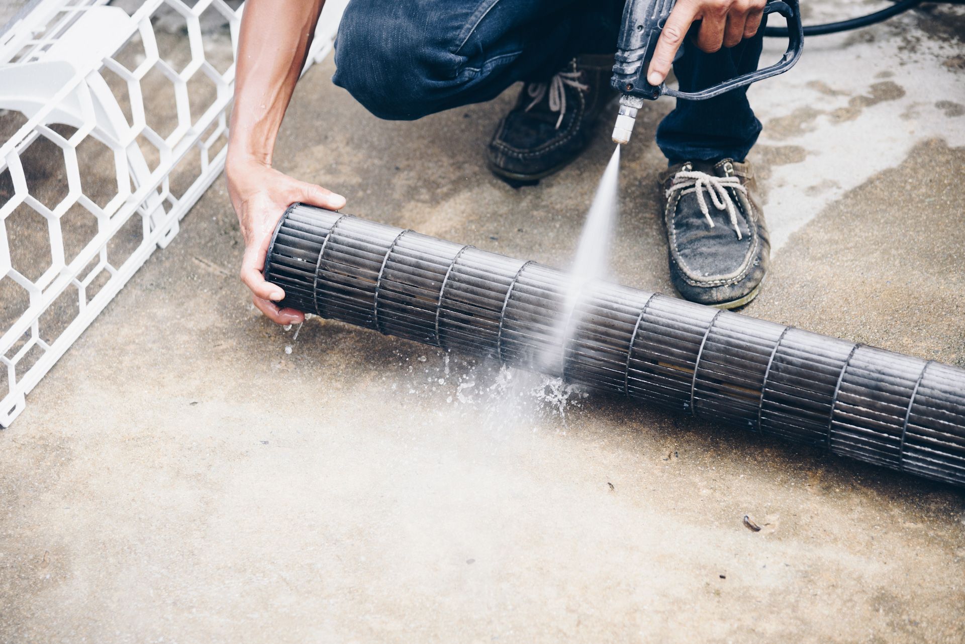 A man is cleaning a fan with a high pressure washer.