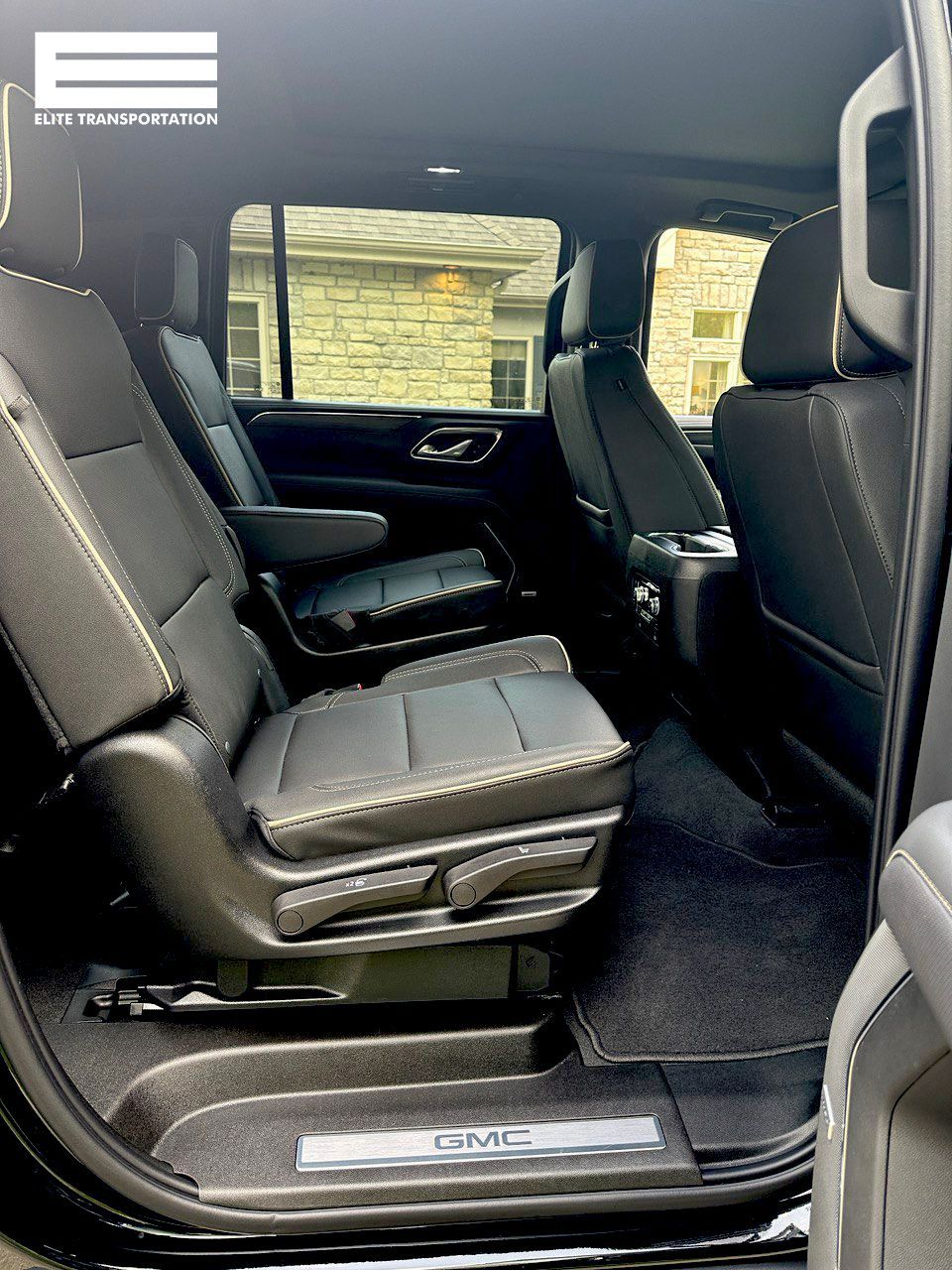 Interior view of a black GMC SUV with black leather seats and black carpet.