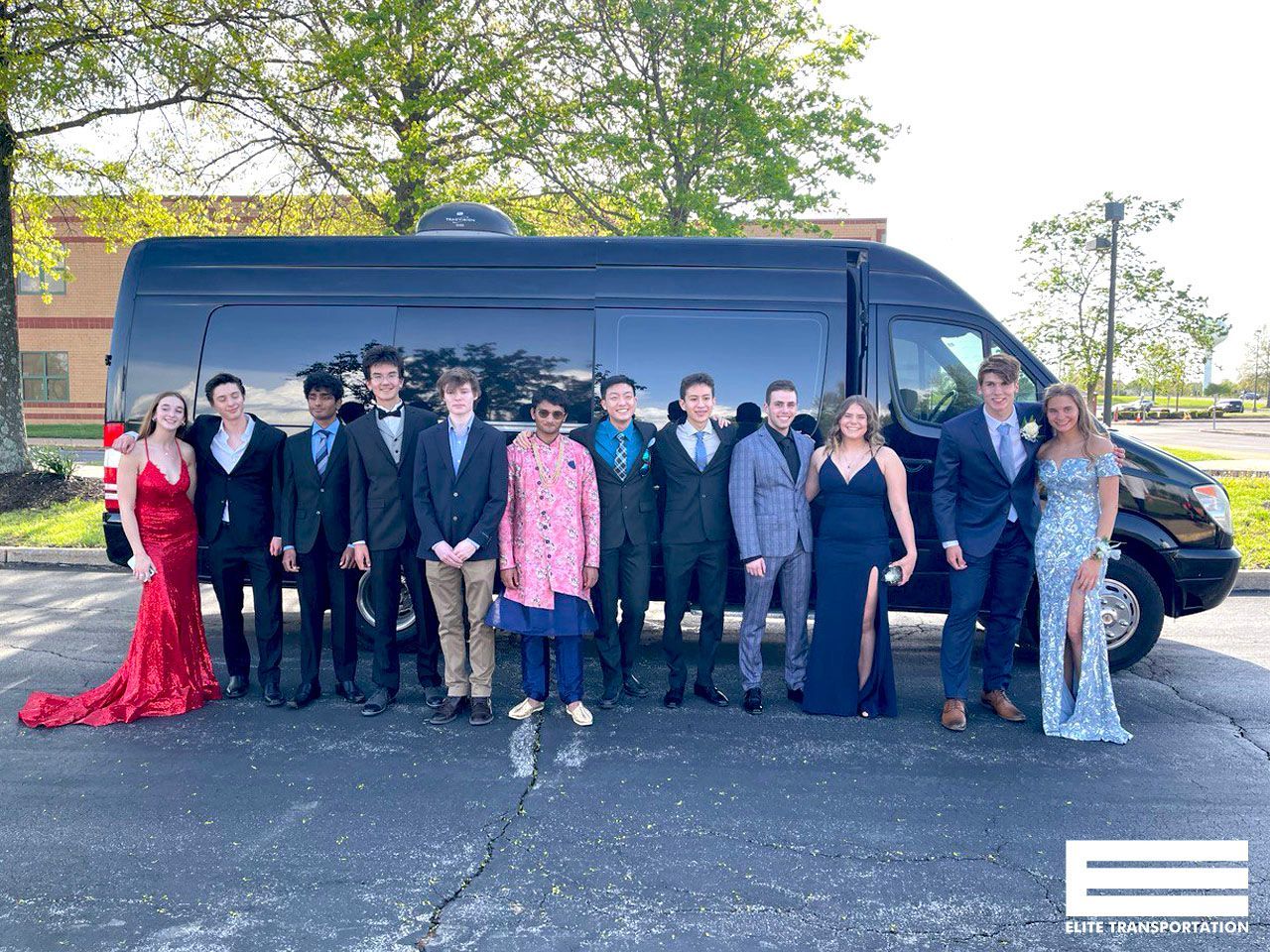Group of formally dressed teens posing by a black van for prom.