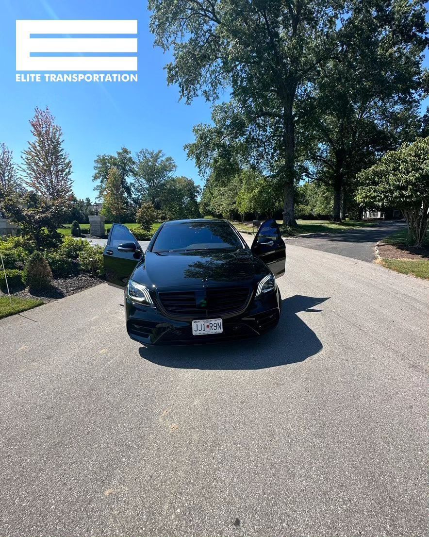 Black car with open doors on a driveway.