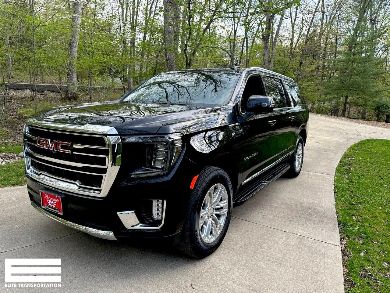 Black GMC Yukon SUV parked on a paved driveway; trees in the background.