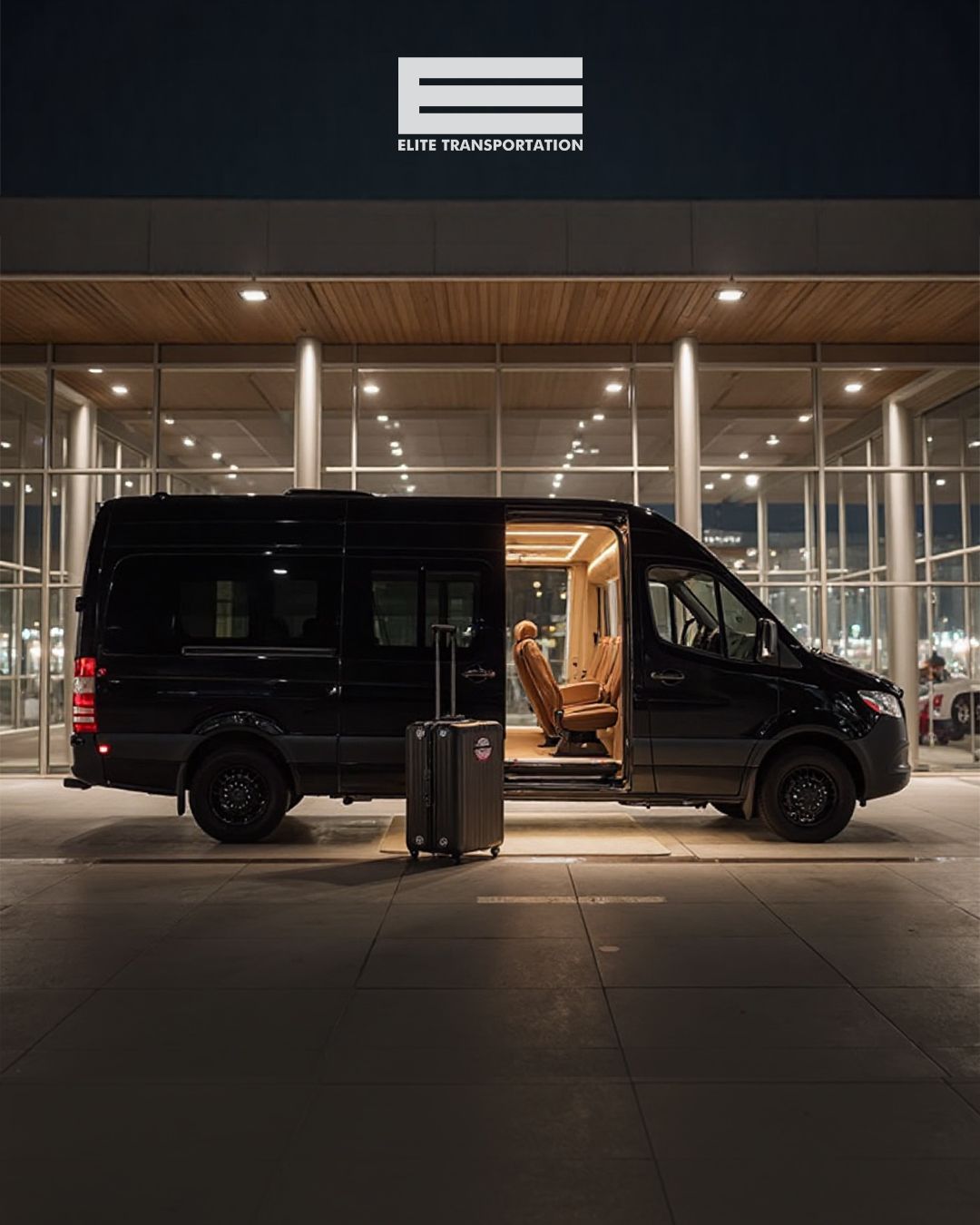Black van parked outside lit building with a suitcase.  