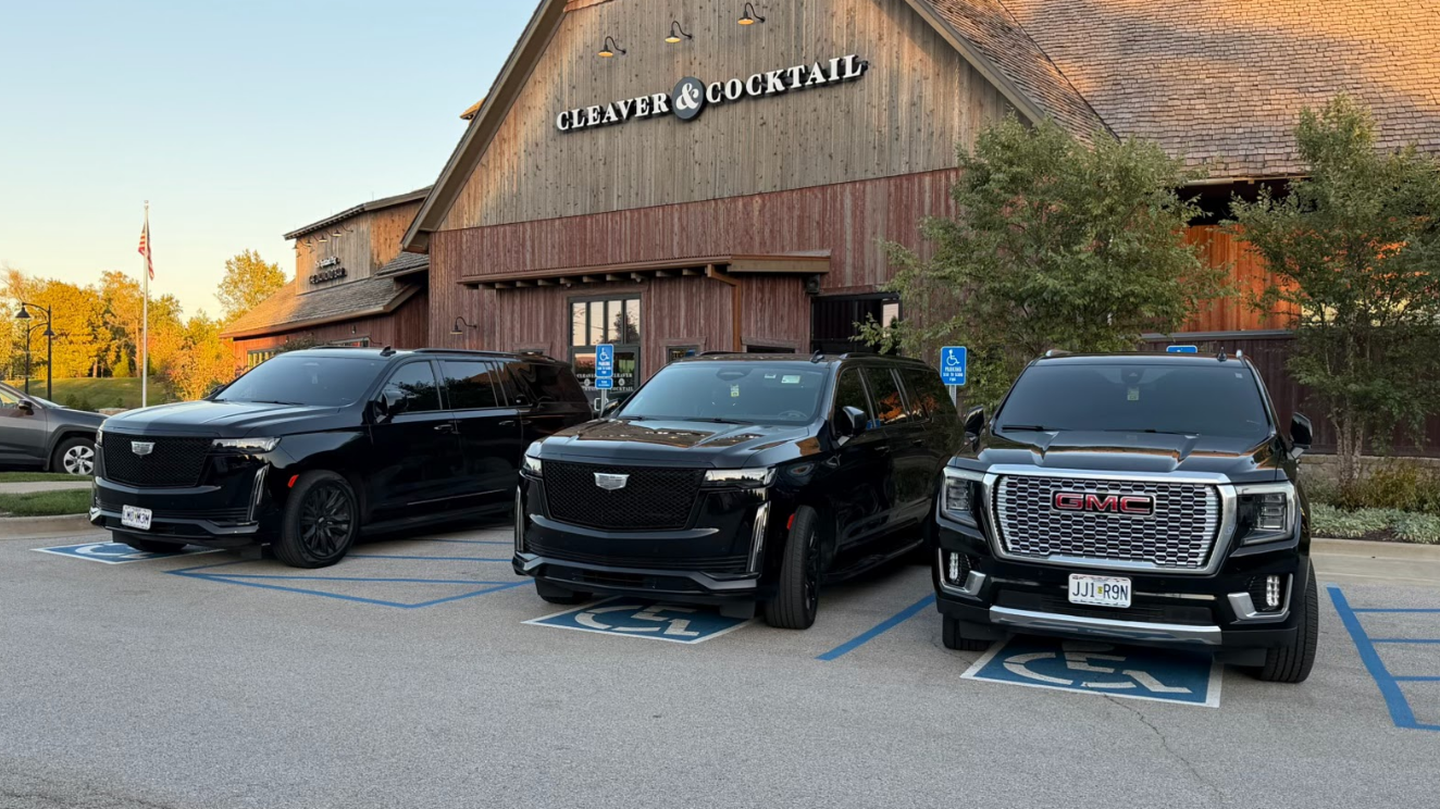 Three black SUVs parked in front of a restaurant with a wooden facade.