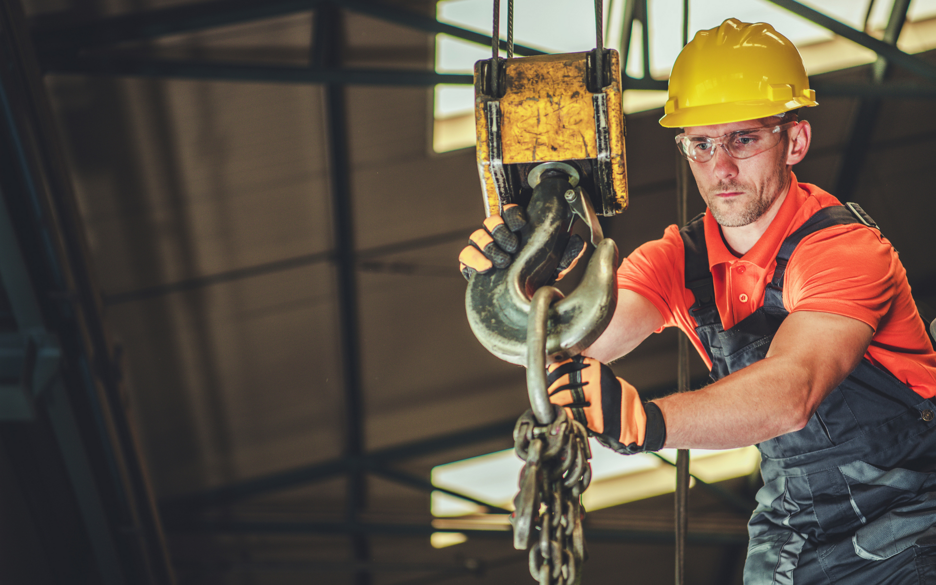 A construction worker is holding a hook on a crane.