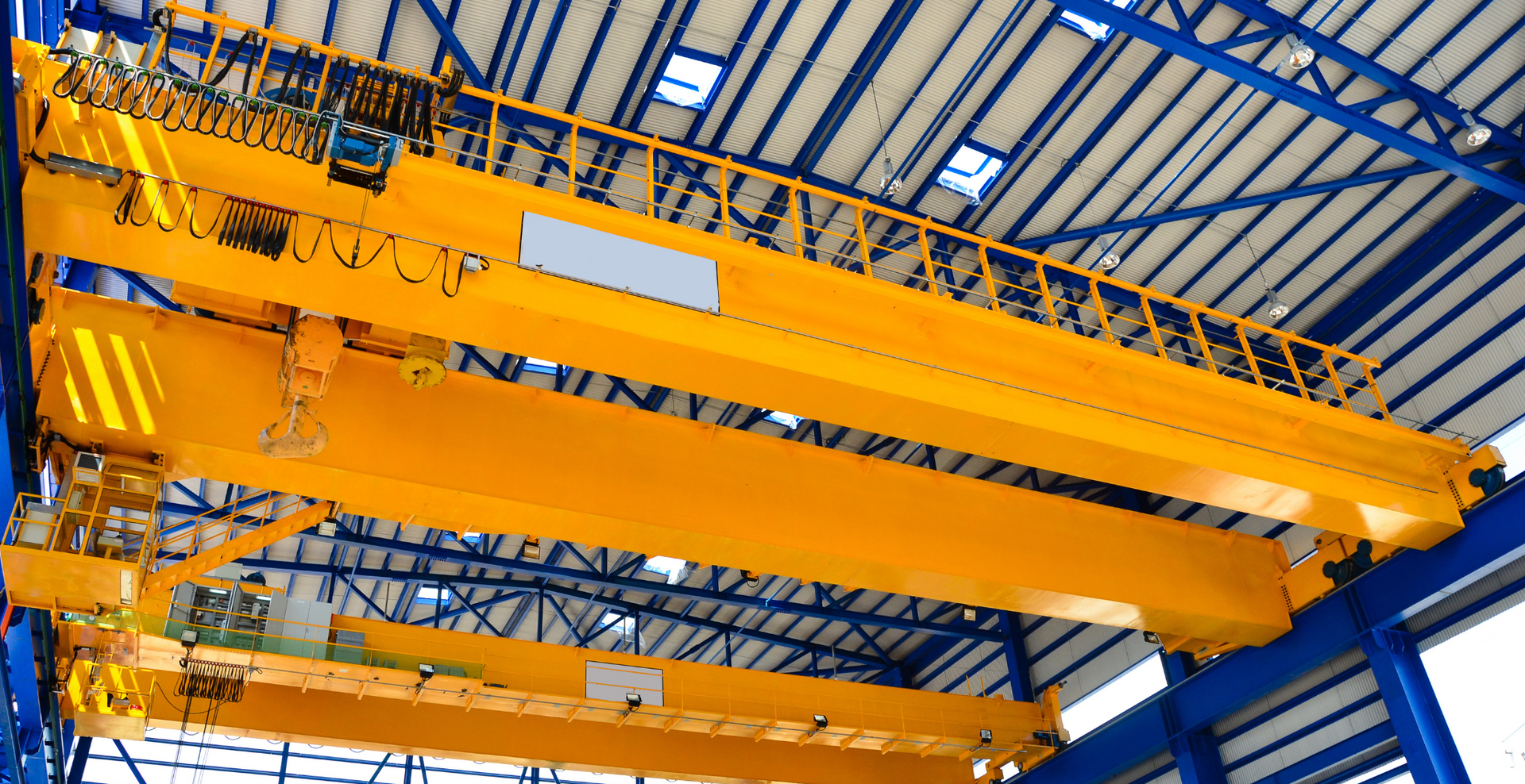 A large yellow crane is hanging from the ceiling of a building.