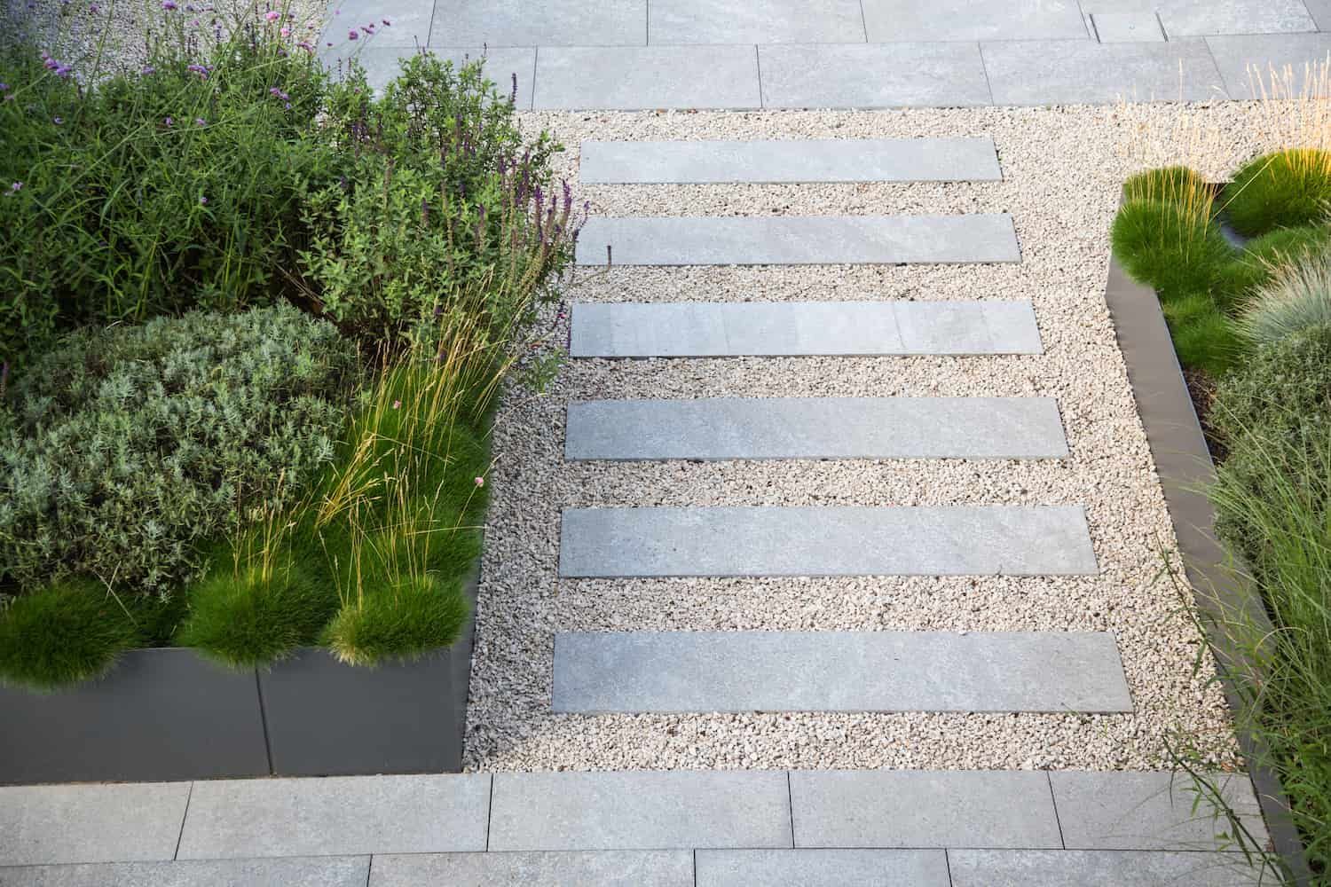 Modern garden pathway with evenly spaced rectangular stone pavers set in light gravel